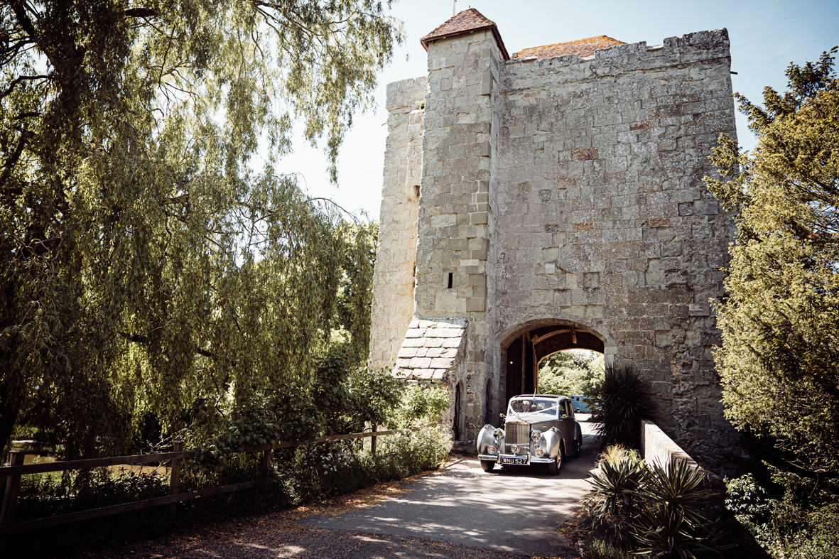 A wedding party enter the gatehouse at Michelham Priory, a wedding venue in East Sussex.